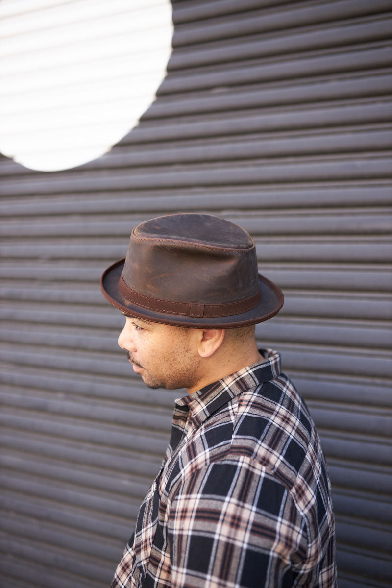 A man in checkered polo wearing  Soho Cholate Leather hat