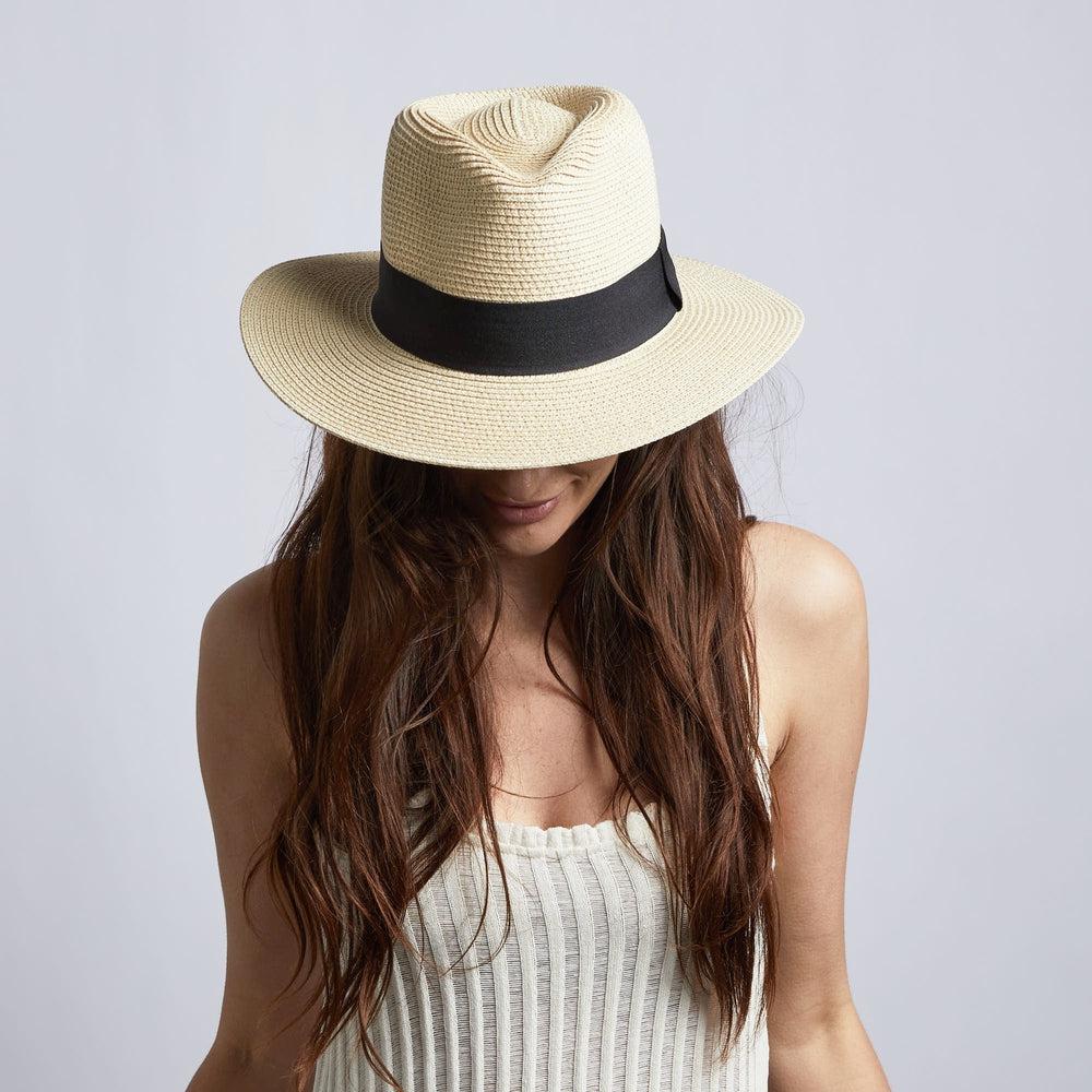 A female model wearing an off white sleeveless and a cream straw sun hat
