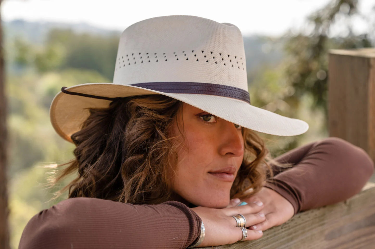 Pretty woman leaning on fence wearing the Barcelona womens wide brim hat by American Hat Makers
