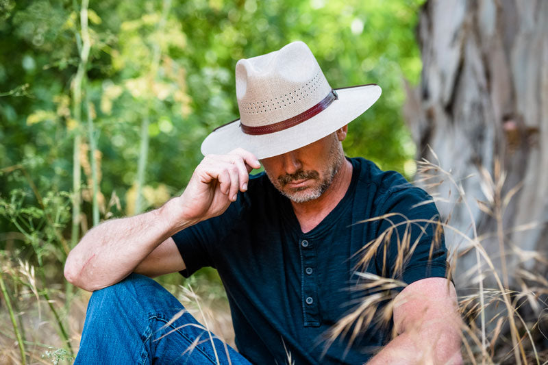 A man sitting down wearing a tan sun hat