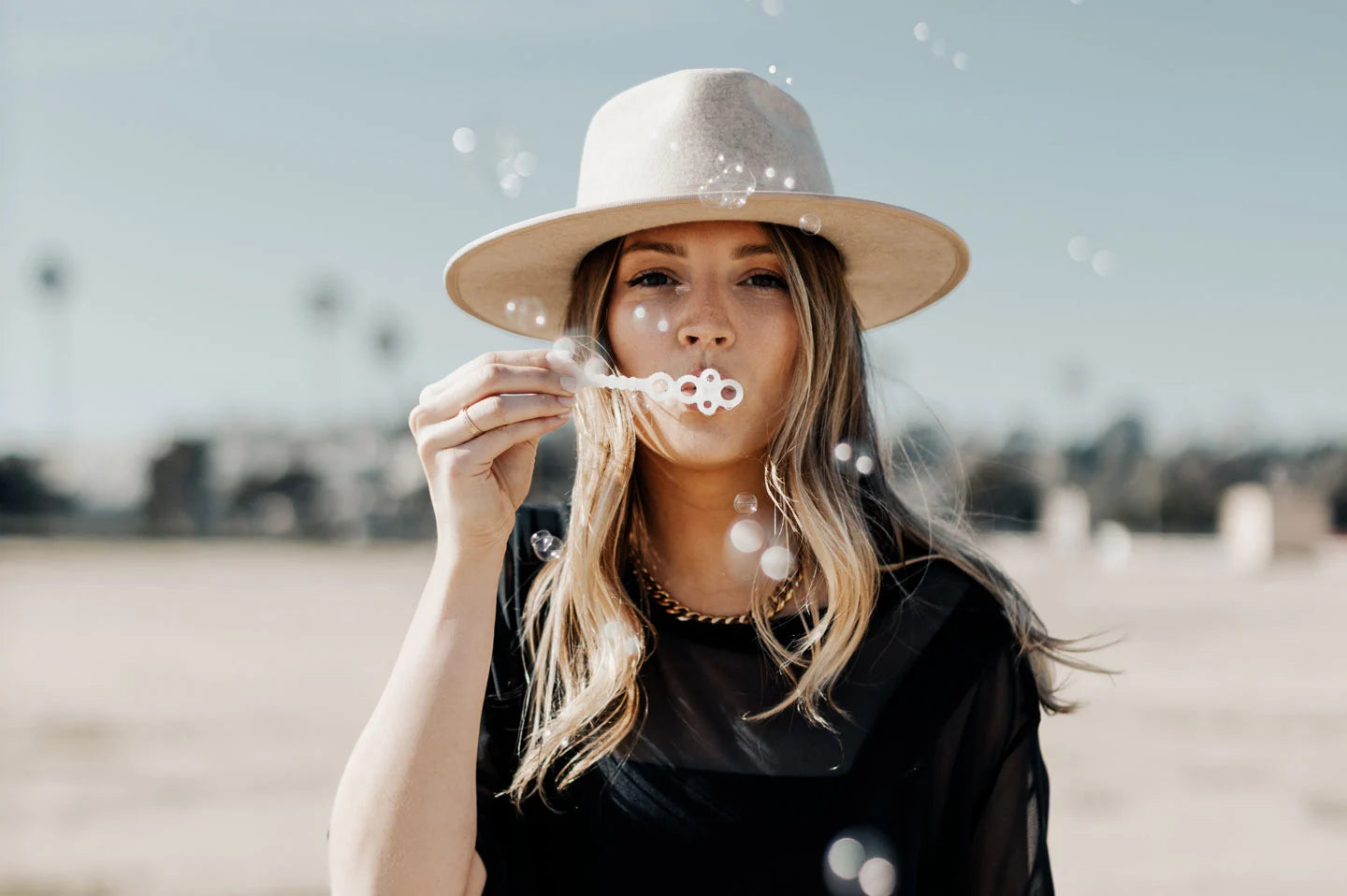 Woman blowing bubbles wearing the Bondi festival hat by American Hat Makers