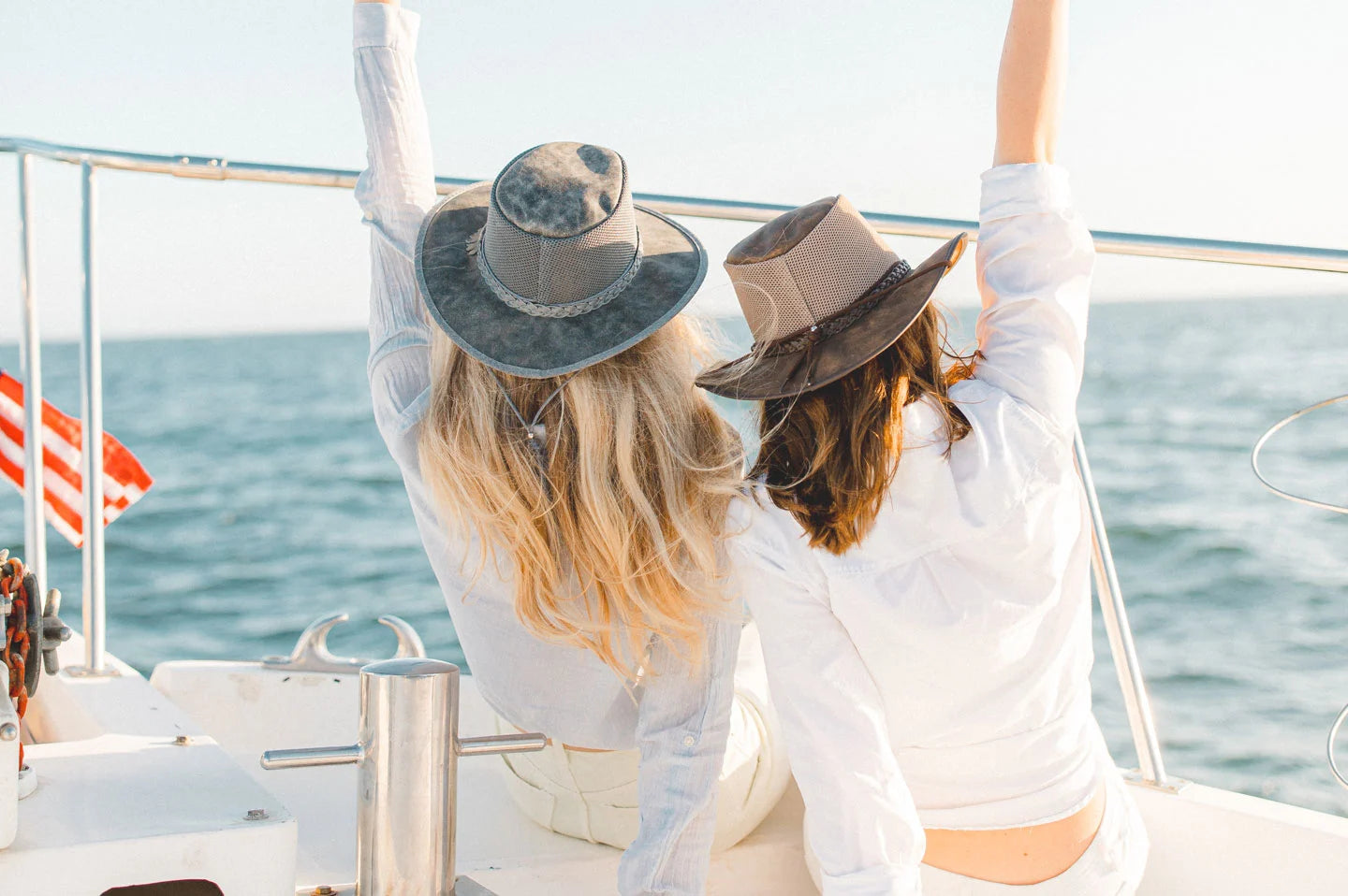 Women sitting on boat wearing the Breeze hat by American Hat Makers in grey and brown