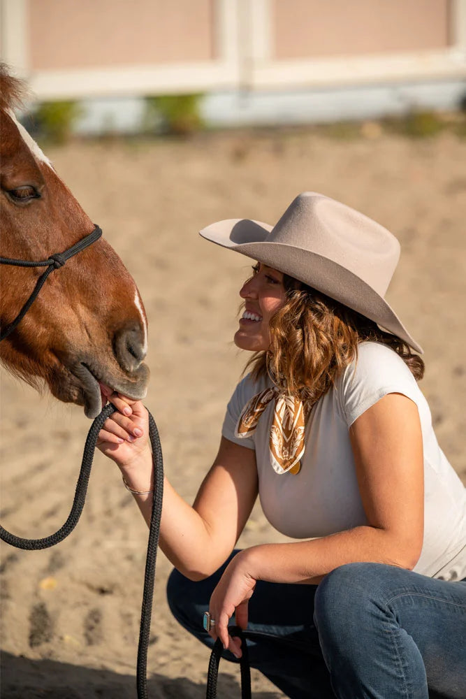 Woman petting horse while wearing the Cattleman cowgirl hat