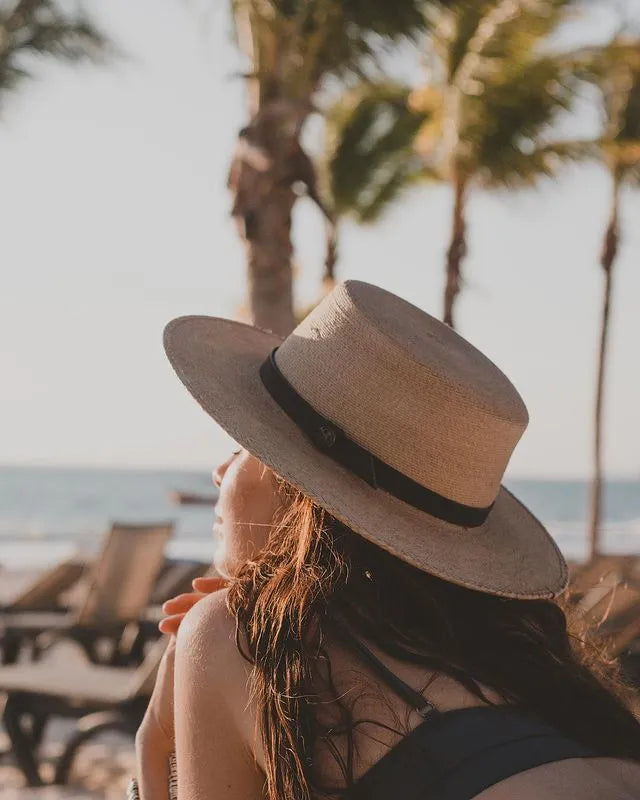 A young woman sunbathing on the beachside with her straw sun hat