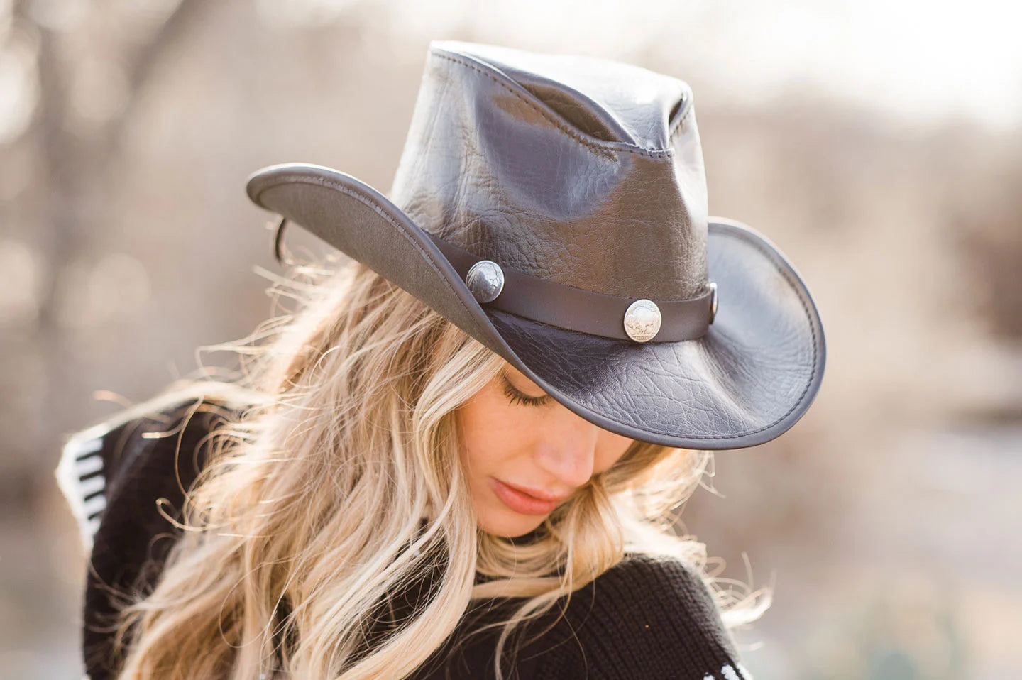 woman in a black blouse and blonde hair wearing a leather black cowboy hat