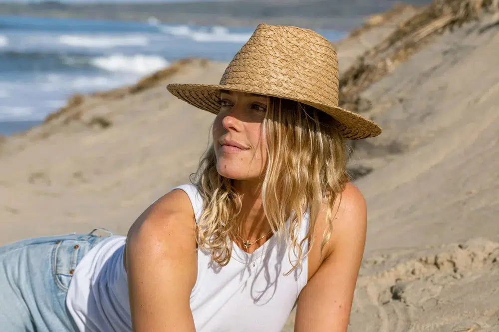 A woman chillin on the beach wearing a straw sun hat