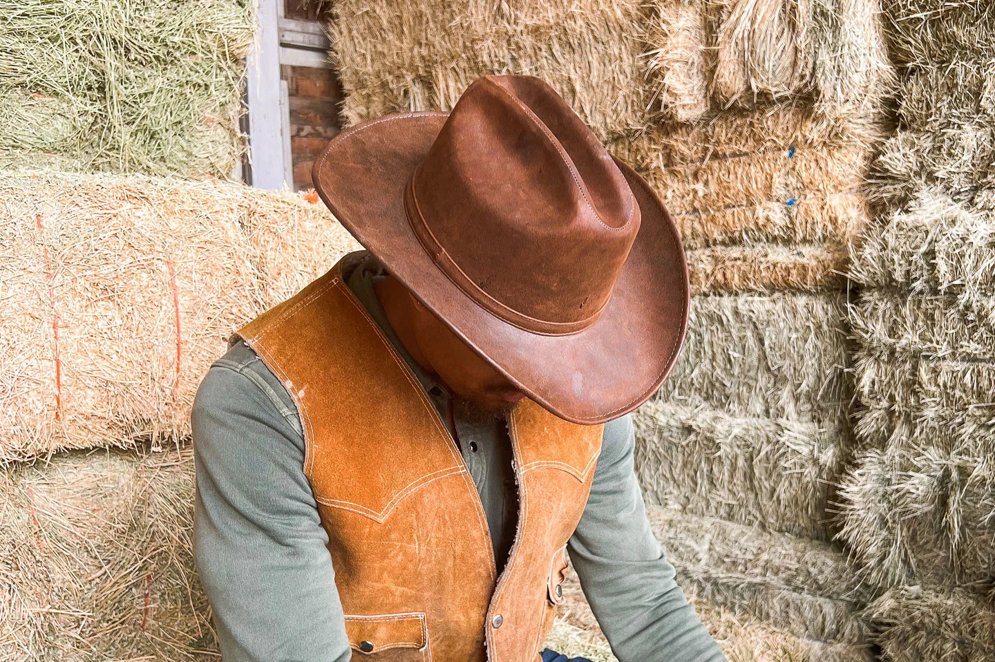 Man sitting in hay bales wearing the Gorge mens cowboy hat by American Hat Makers