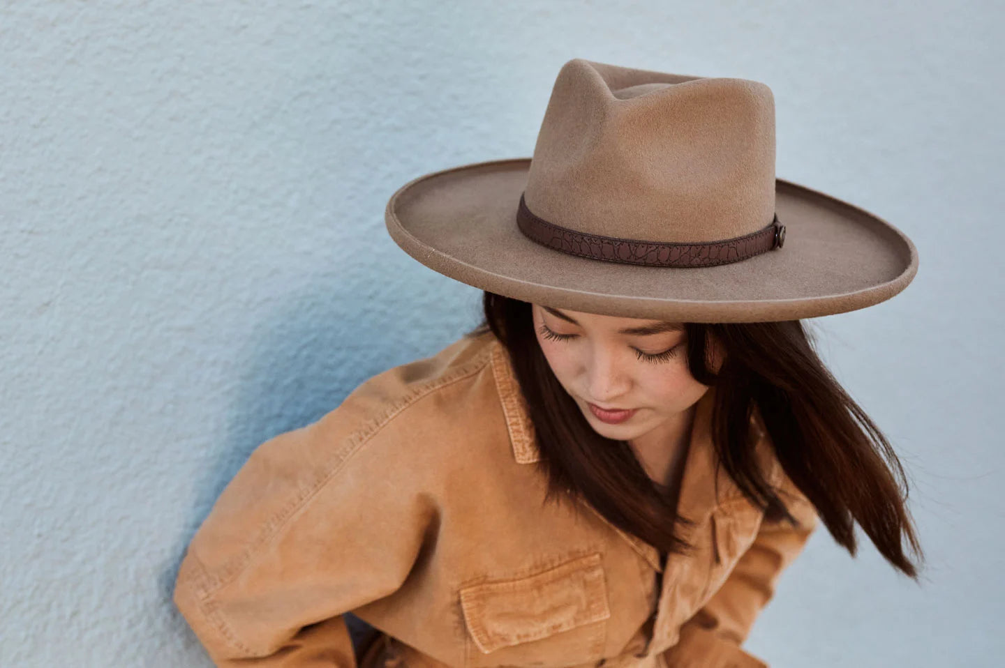 Woman leaning against wall wearing the Hudson womens wide brim hat by American Hat Makers