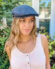 A woman wearing the Mikey Womens Charcoal Cap along with a white sleeveless top
