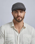 A man wearing a white polo and the Mikey Mens Charcoal Cap