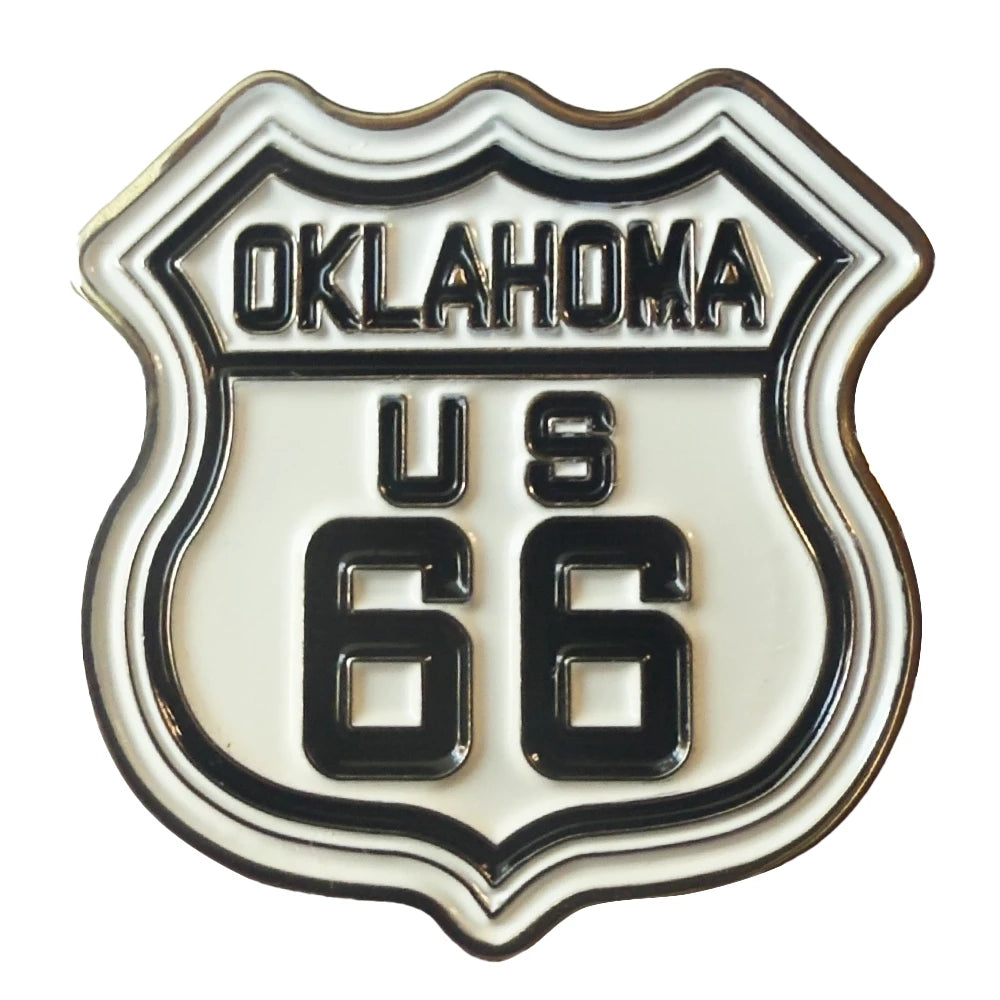 An enamel shield-shaped pin featuring the 'Oklahoma US 66' Route 66 design, with black lettering and border on a white enamel background.