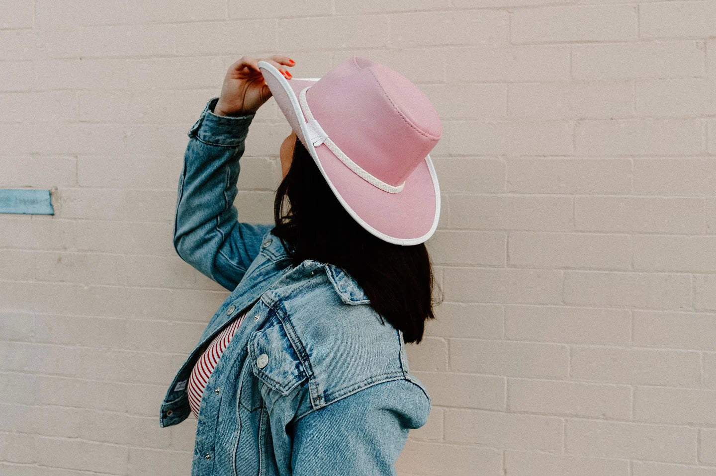woman in a blue denim jacket wearing a pink hat by american hat makers