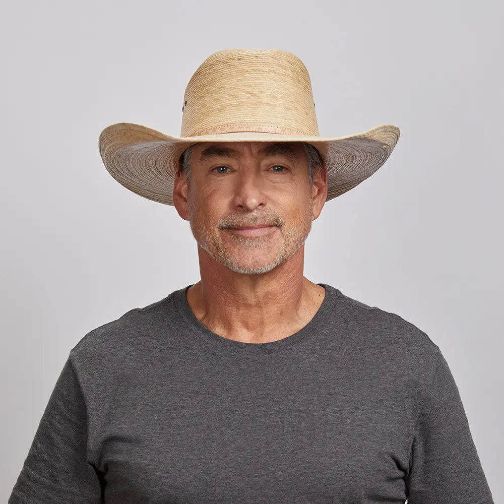 A man in a gray top wearing a cream palm cowboy hat