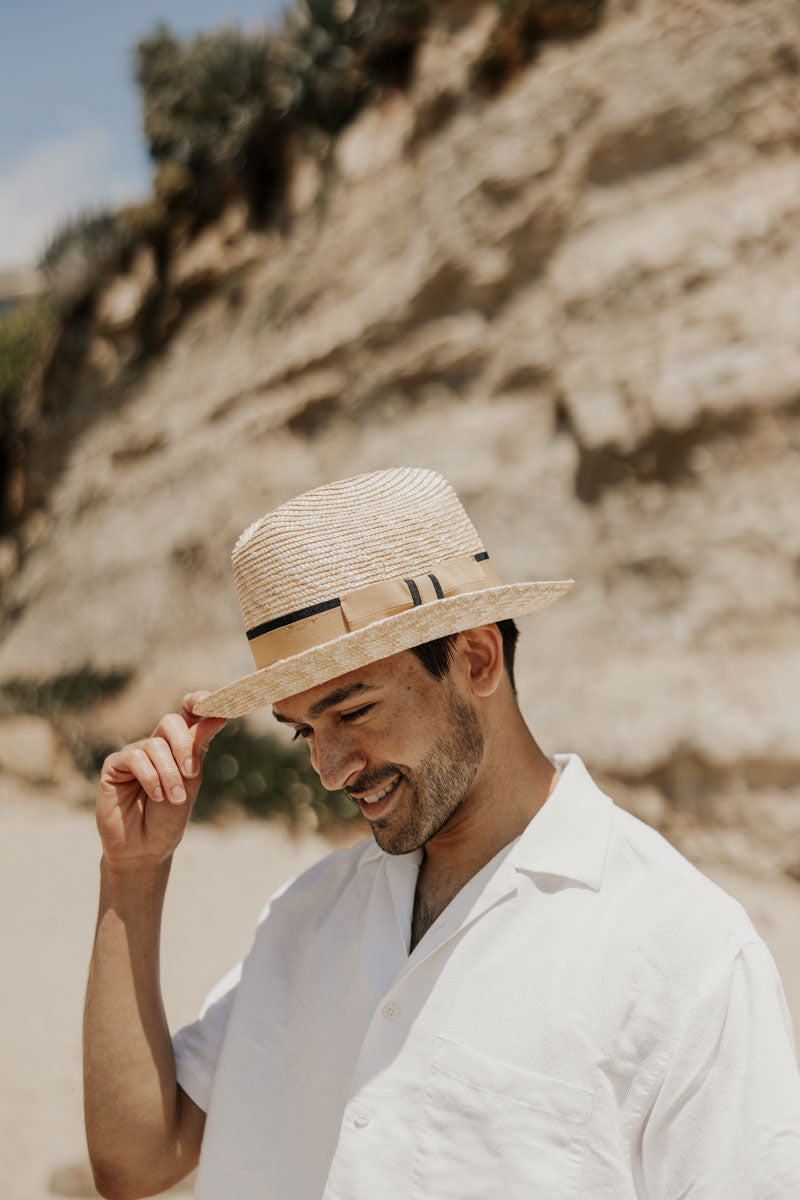 A man wearing white polo and a straw sun hat