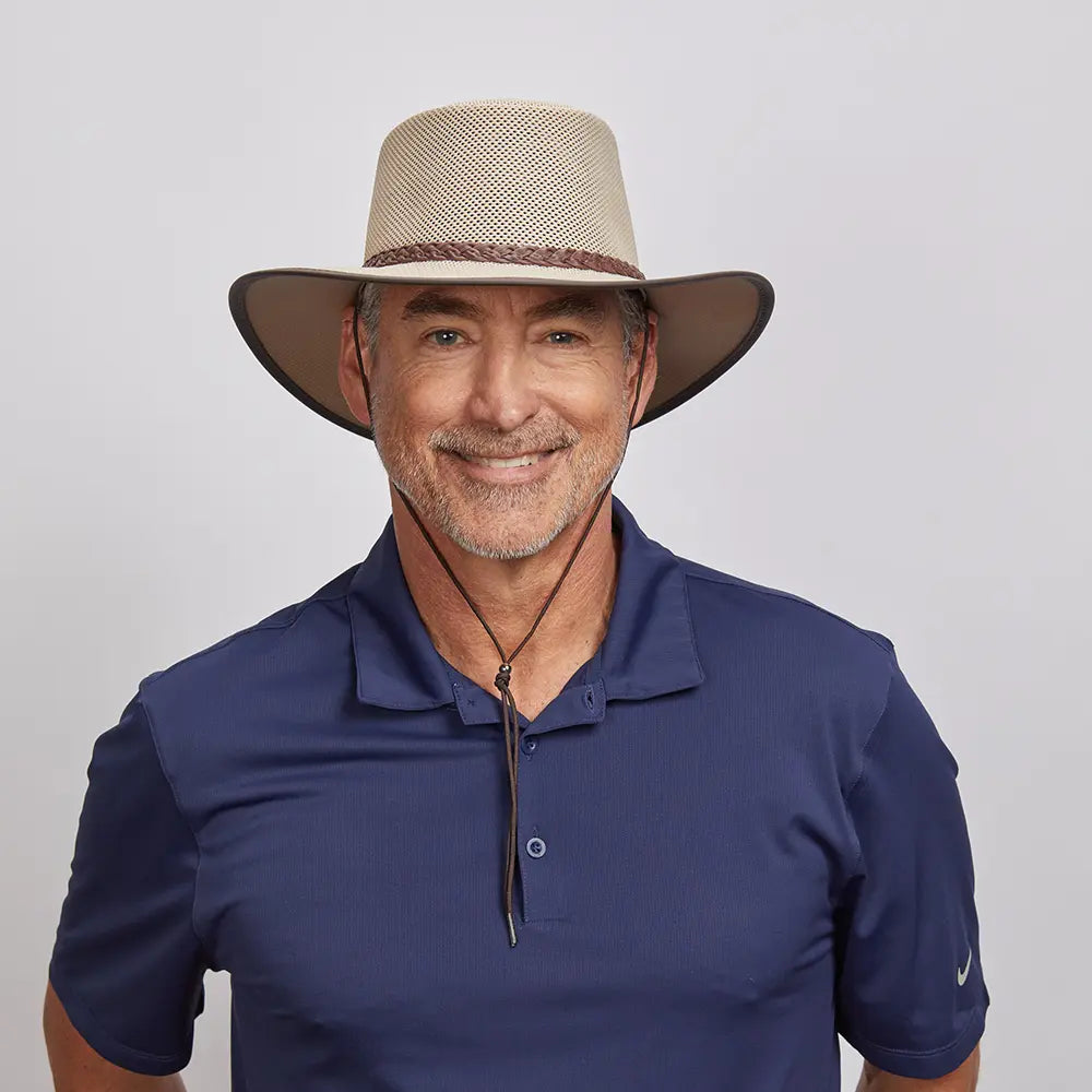 Middle-aged man with a friendly smile, wearing a beige mesh hat and a dark blue polo shirt