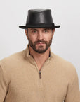 Man with a light stubble wearing a Soho Fedora Hat and beige zip-up sweater