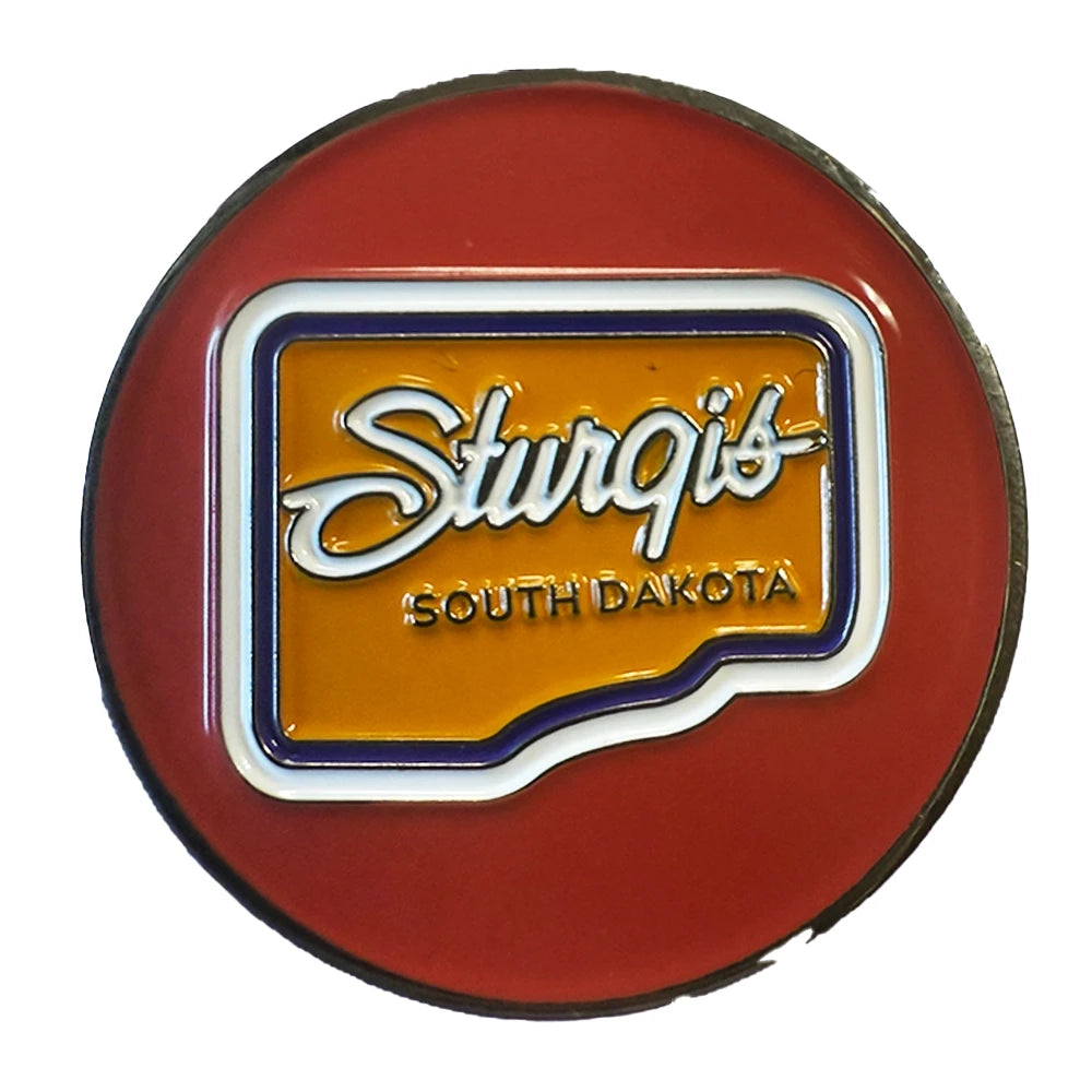 A circular red Sturgis South Dakota novelty pin or badge featuring a yellow-orange center with white script lettering and blue border details, shown on a plain white background.