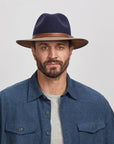 A man wearing the Summit Navy Felt Leather Fedora Hat
