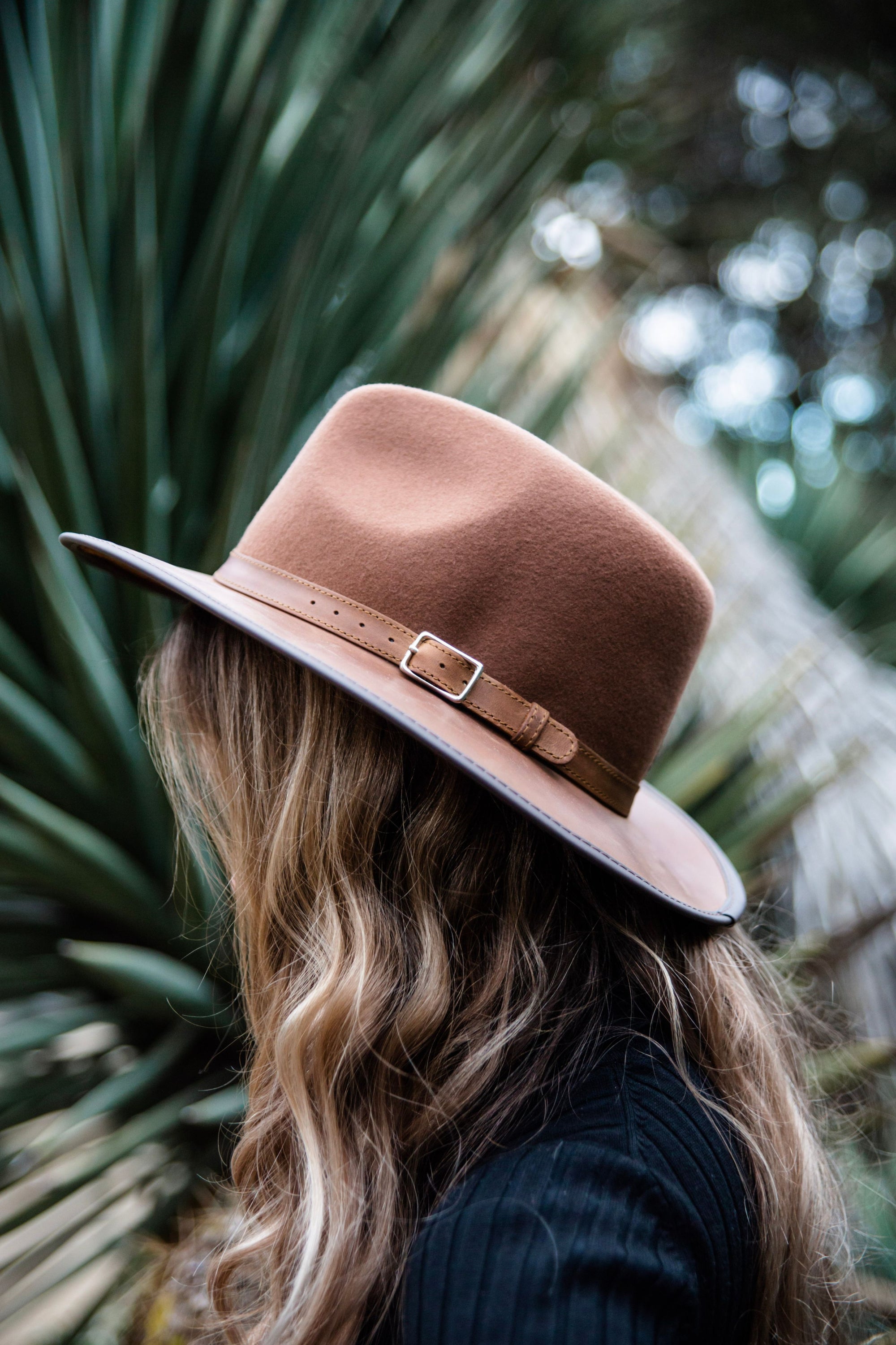 A woman on a side view wearing brown felt leather hat