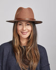 Woman with long brown hair wearing a Saddle Felt Fedora Hat and a navy blue sweater.