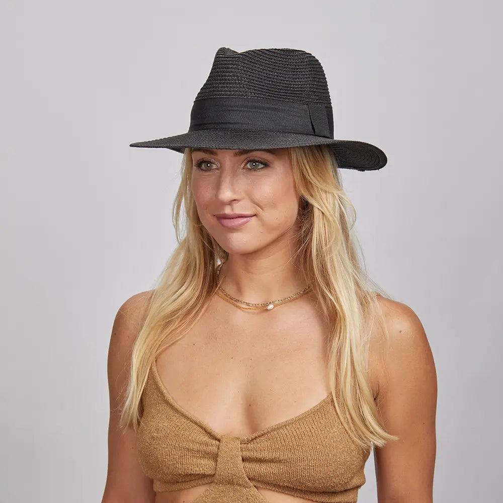 A blonde woman wearing a Black Afternoon Fedora Hat and a brown knitted top.