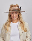 A woman wearing a white shirt paired with a textured beige jacket and the Tornado Fedora Hat