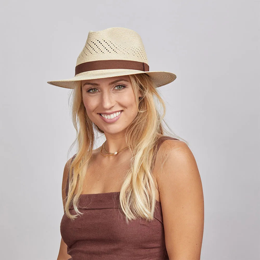 A smiling model wearing a brown sleeveless and a natural colored panama sun hat