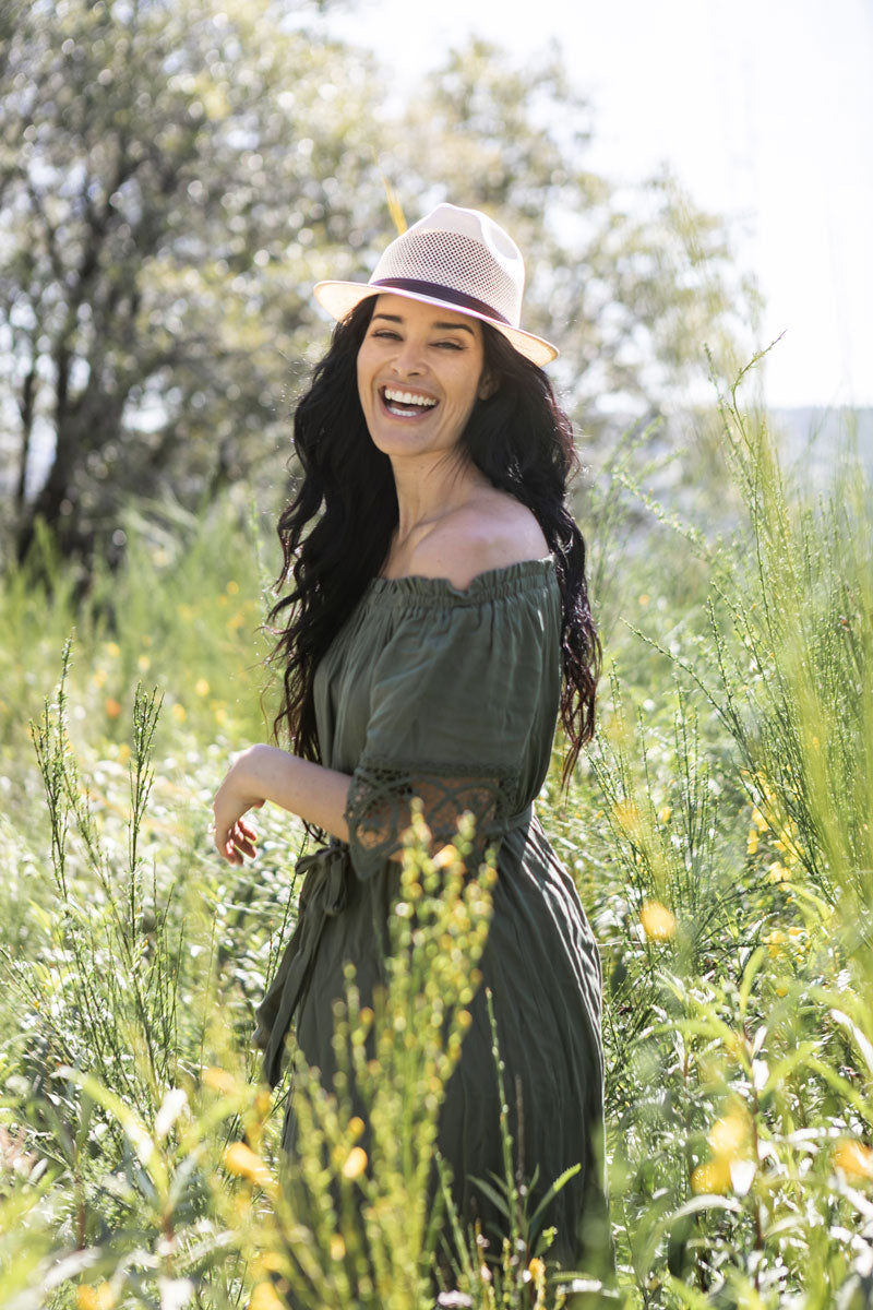 A woman in a grass field wearing tuscany cream sun hat