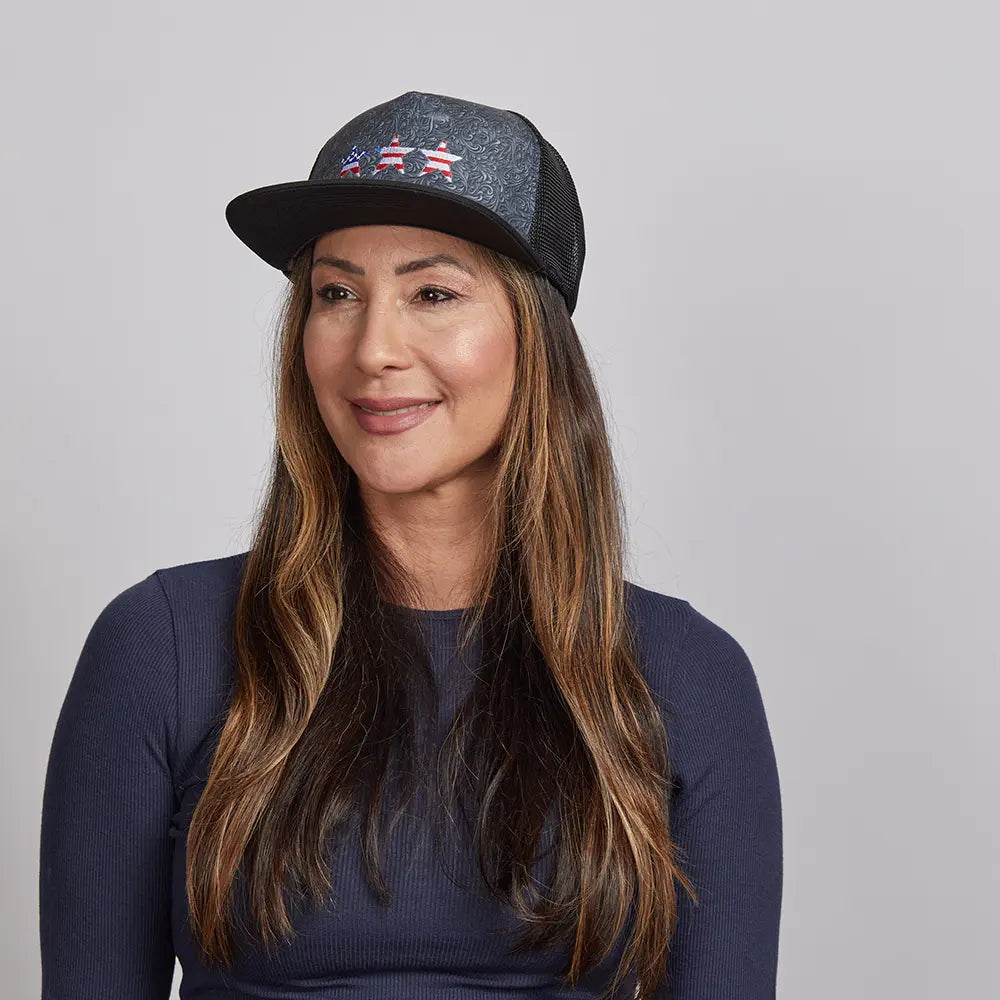 A long haired woman wearing a navy blue top and a mesh poly cap