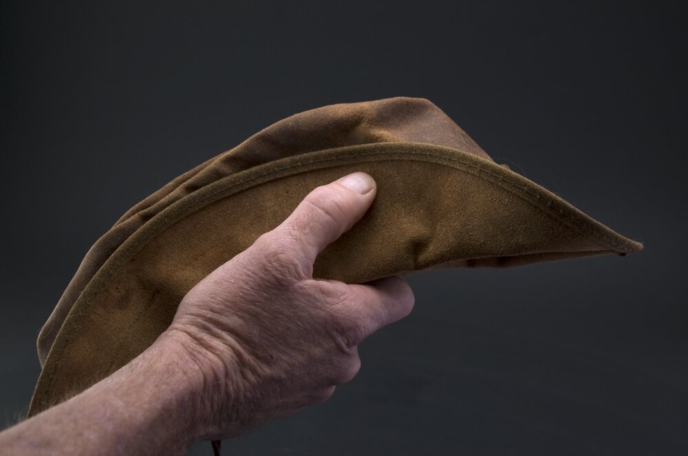 A hand holding a brown hat