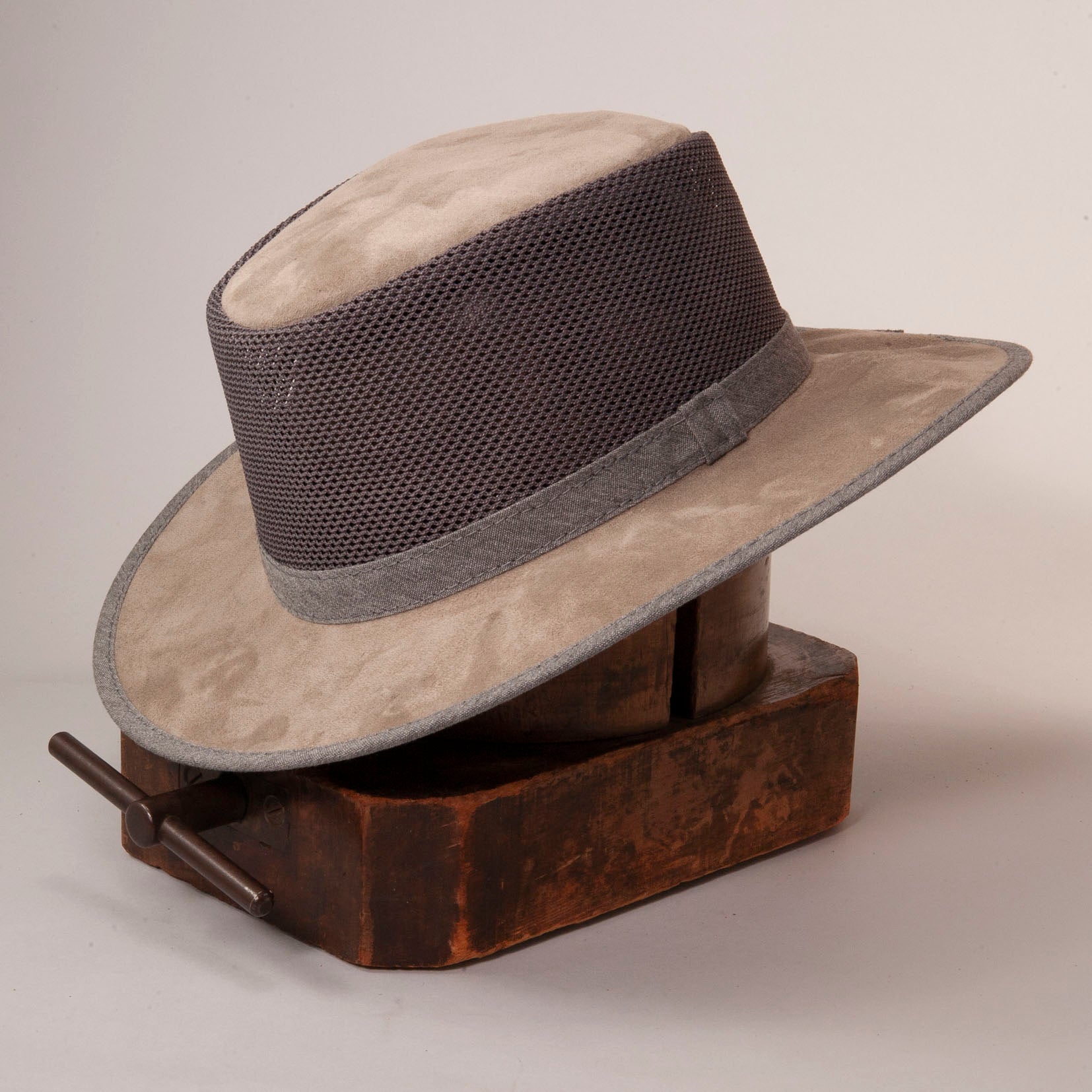 An angle side view of a misty suede mesh sun hat placed on a wood stand