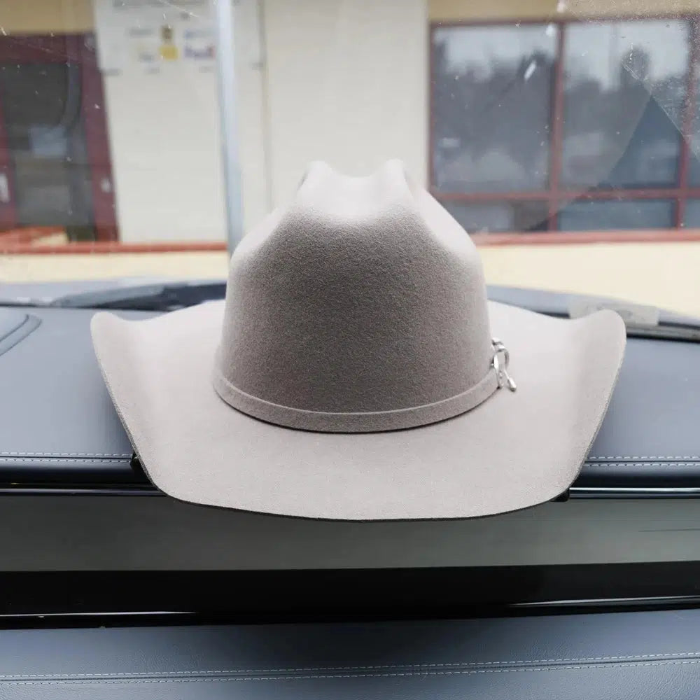 A white colored felt hat placed on a car's dashboard