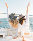 Two woman sitting on a boat wearing polo shirts and hats