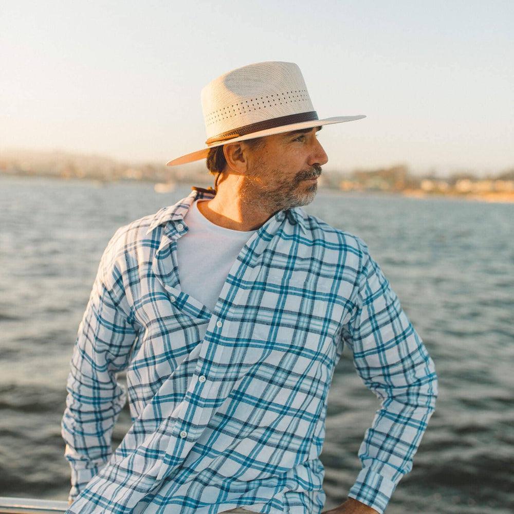 A man on the boat wearing checkered polo and a Straw Sun Hat 