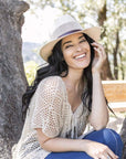 A woman sitting under the tree with a knitted blouse and Cream Straw Fedora Hat 
