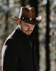 A man walking in the forest wearing Cobblestone Leather Cowboy Hat with 3" Brim and 4" Crown 
