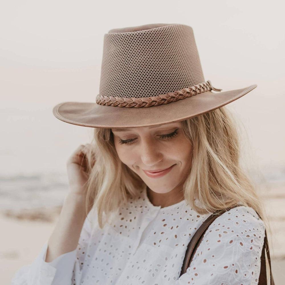 A woman on a beach wearing white blouse and a Copper Leather Mesh Sun Hat