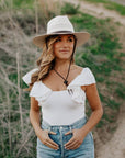 A woman standing outdoors wearing Barcelona Cream Straw Sun Hat 