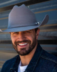 A smiling man wearing denim jacket and a Gunsmoke Cattleman Felt Cowboy Hat 