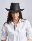 A woman looking downwards wearing Black Outback Leather Hat 