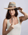 A woman looking front wearing  tan straw fedora cream hat