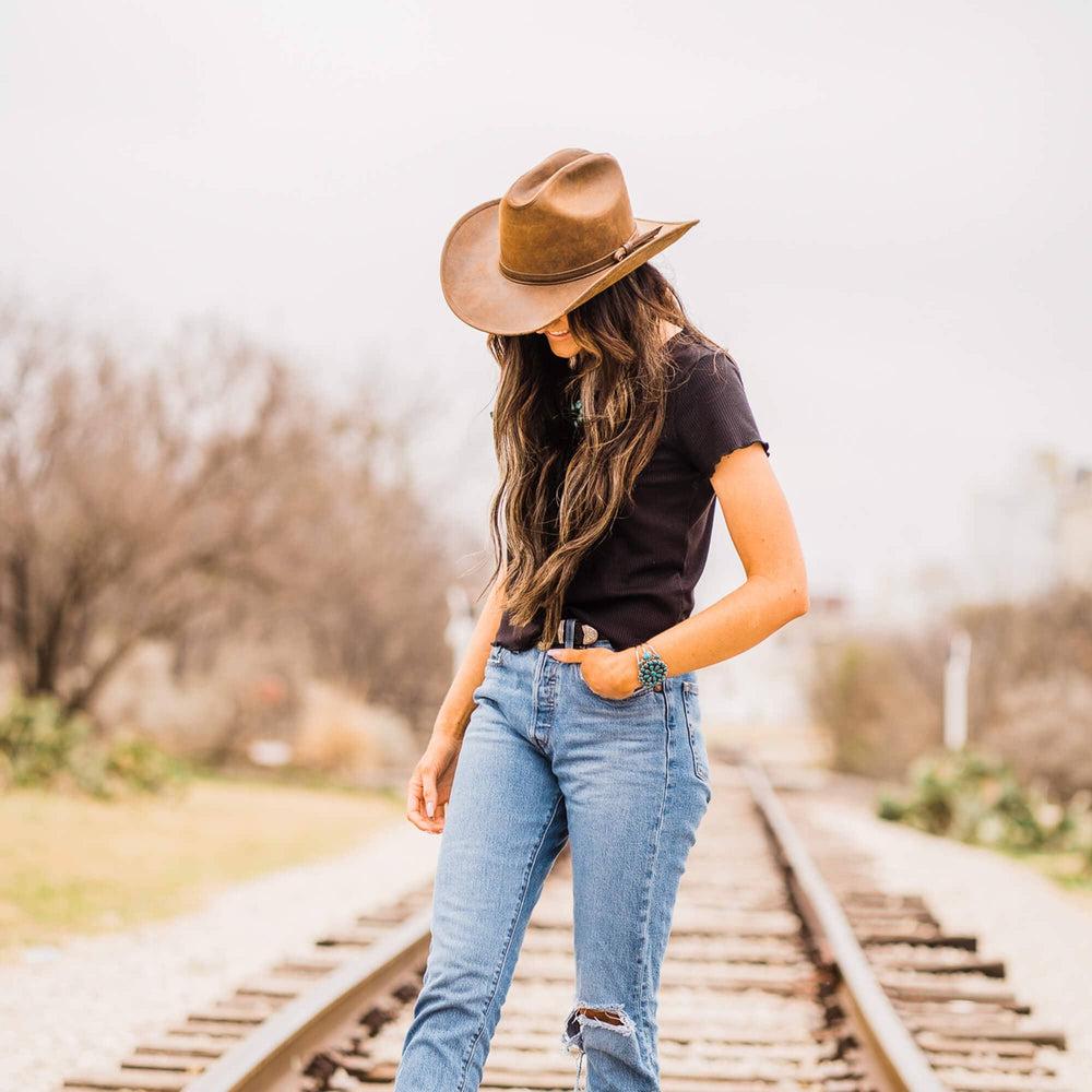 A woman in a rail track wearing black shirt and a Gorge Leather Cattleman Brown Cowboy Hat
