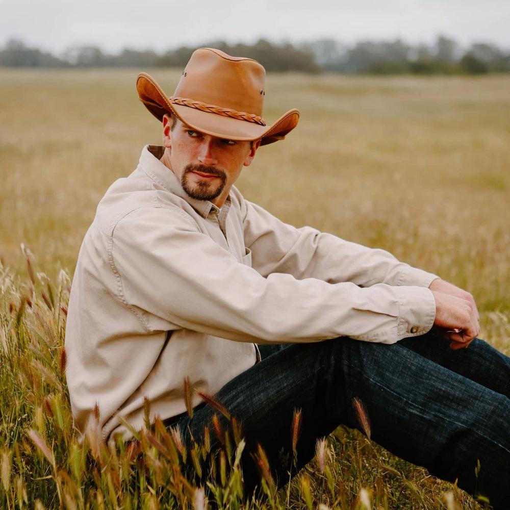 Man sitting in field wearing the Hollywood Copper Leather Cowboy Hat by American Hat Makers