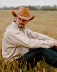 Man sitting in field wearing the Hollywood Copper Leather Cowboy Hat by American Hat Makers