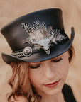 A woman wearing a black top hat with a true grit hat band
