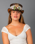A woman wearing a white dress and a top hat with true love beaded hat band