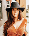 A woman wearing brown blouse and a Midnight Black Rider Leather Hat 