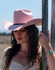 A woman holding a steel fence and wearing Pink Straw Cowboy Hat 