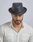 A man looking downwards wearing Soho Black Leather Trilby Fedora Hat