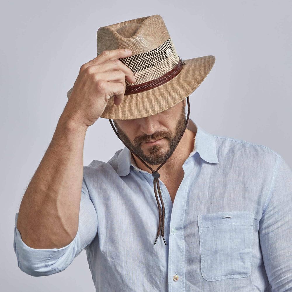 A man looking downwards while wearing and holding Milan Tan Straw Fedora Hat 
